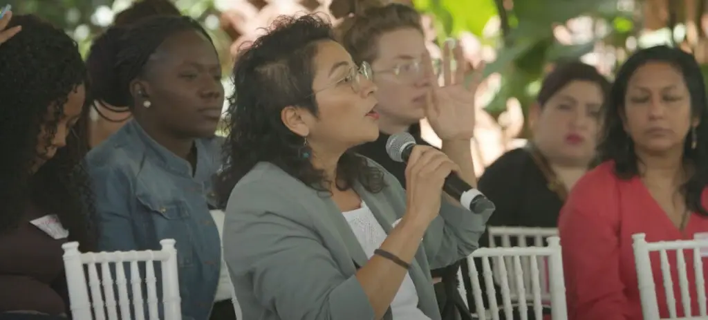 Participant speaking into a microphone during a public discussion – Co-Impact website