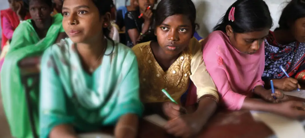 A group of girls sitting at their desks inside a classroom | Co-Impact.