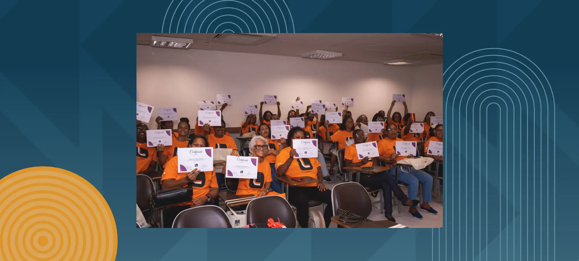 Group of smiling older women holding up their certificates in a classroom, all wearing orange t-shirts.