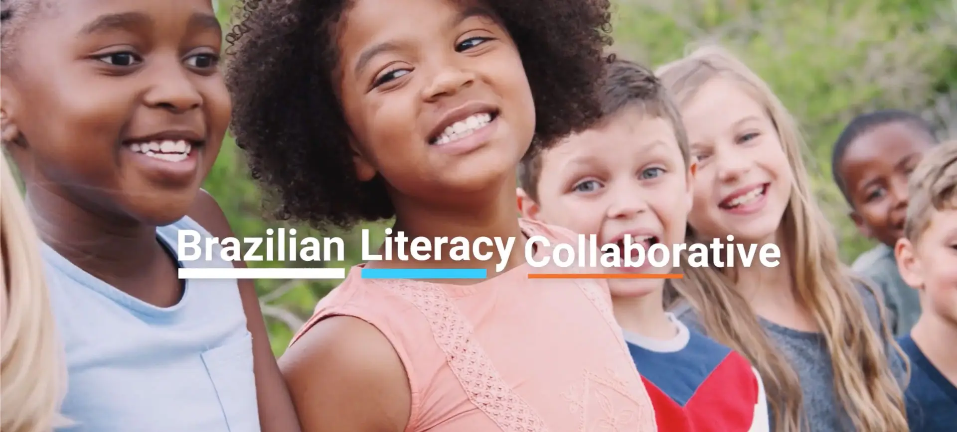 Group of diverse smiling children of different ethnicities embracing outdoors with "Brazilian Literacy Collaborative" text overlay in white letters with colorful underlines