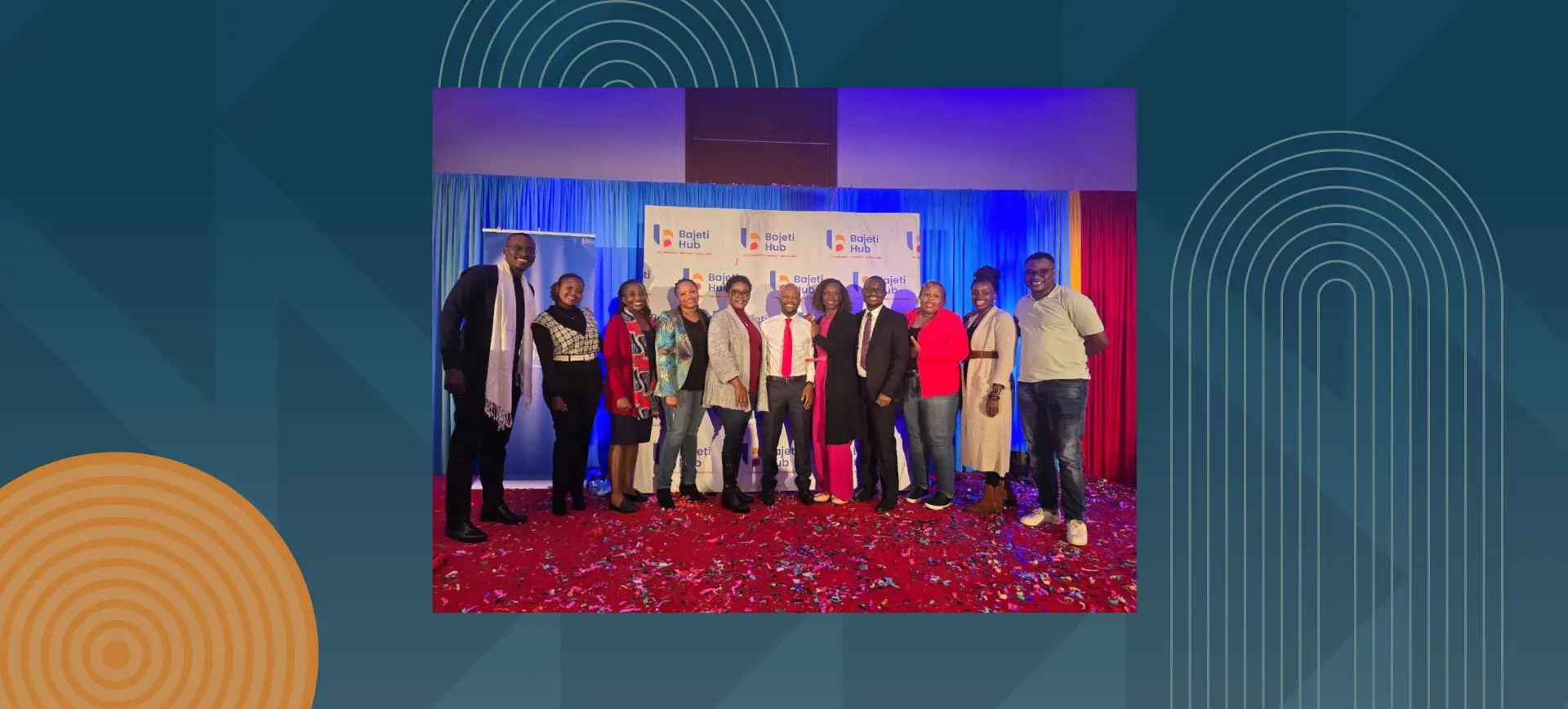 Group of professionals posing on stage with Bajeti Hub branding and colorful lighting backdrop