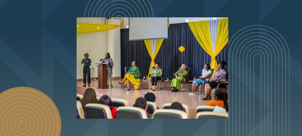 Panel discussion event with speakers at podium and seated panelists in colorful traditional attire before audience