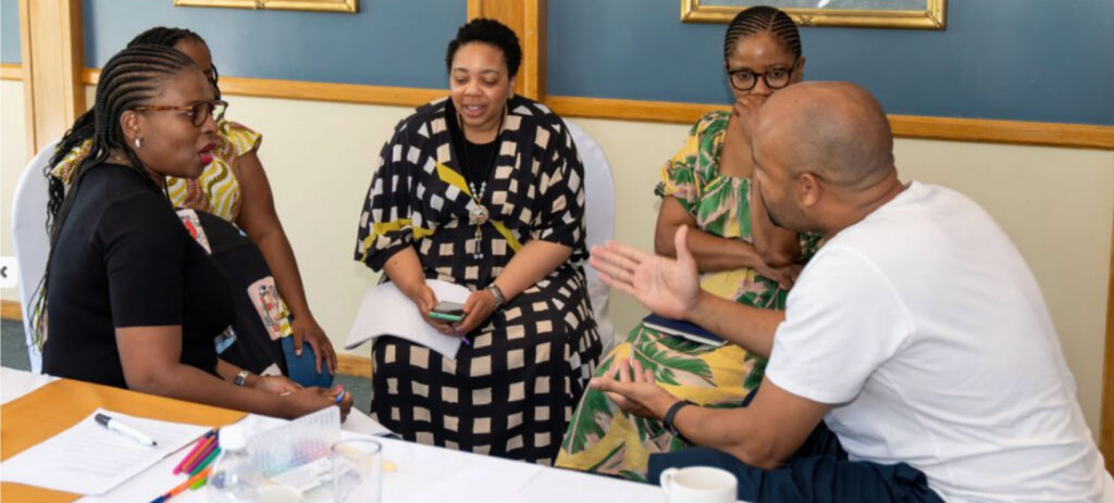 Four African professionals in business meeting discussion around conference table in formal office setting