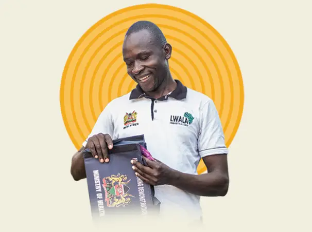 A man smiling while holding a folder | Co-Impact.